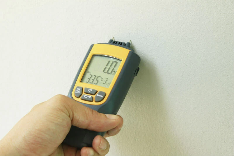 professional damp surveyor testing the walls of a home. Moisture readings are showing 1.0%.