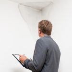 Mature man examining damp patch on wall